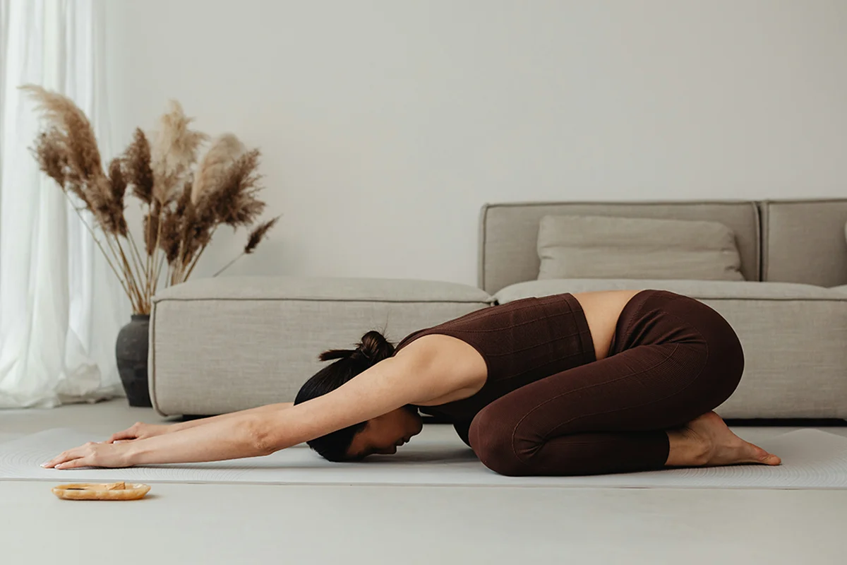 Person practicing gentle yoga and mindful breathing by sunny window